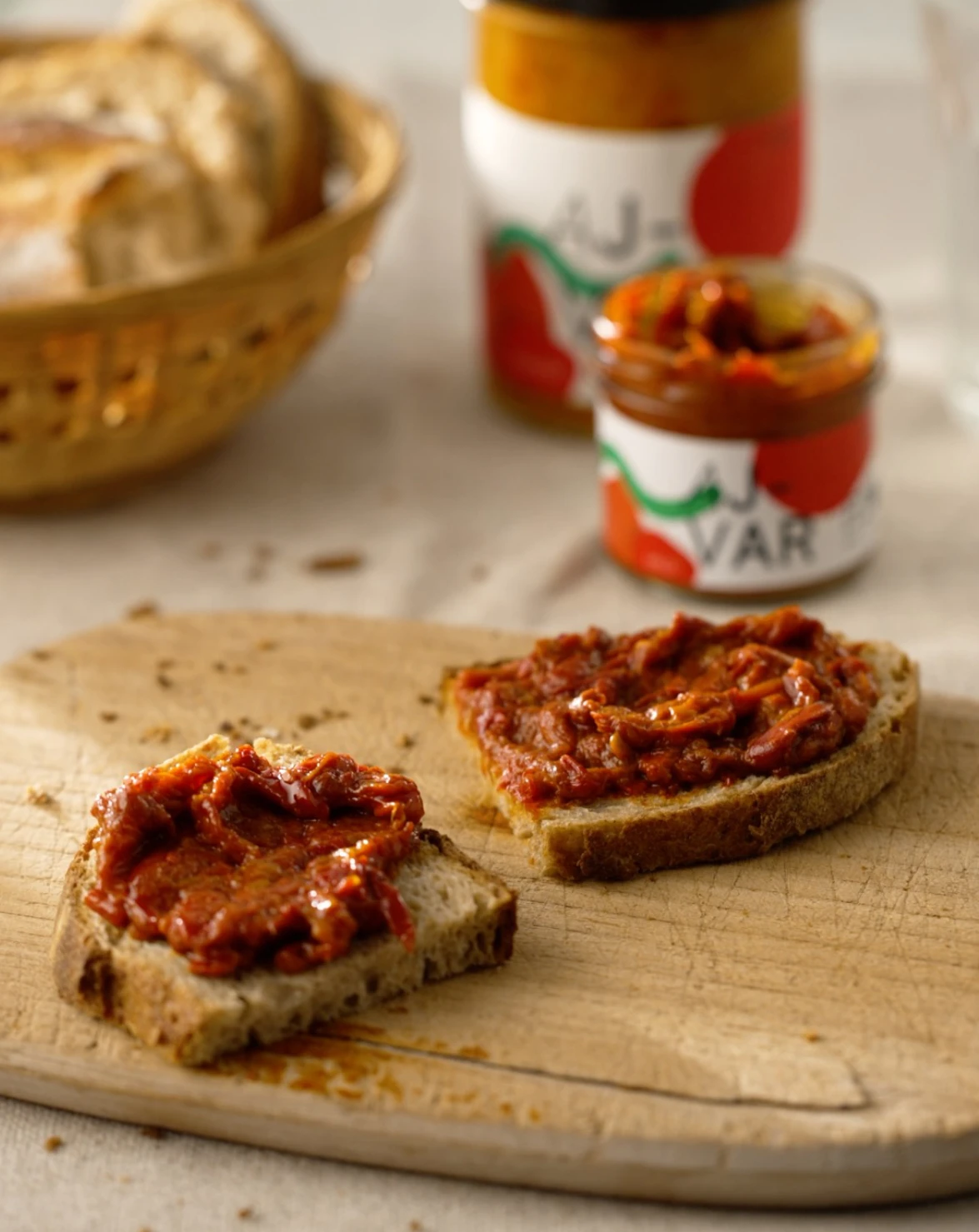 Brot, mit Bio Ajvar gestrichen, auf gedecktem Frühstückstisch